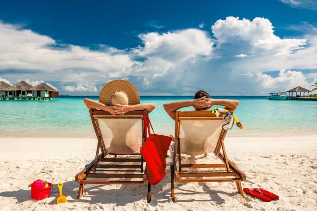 A couple relaxing at the beach sitting on beach chairs