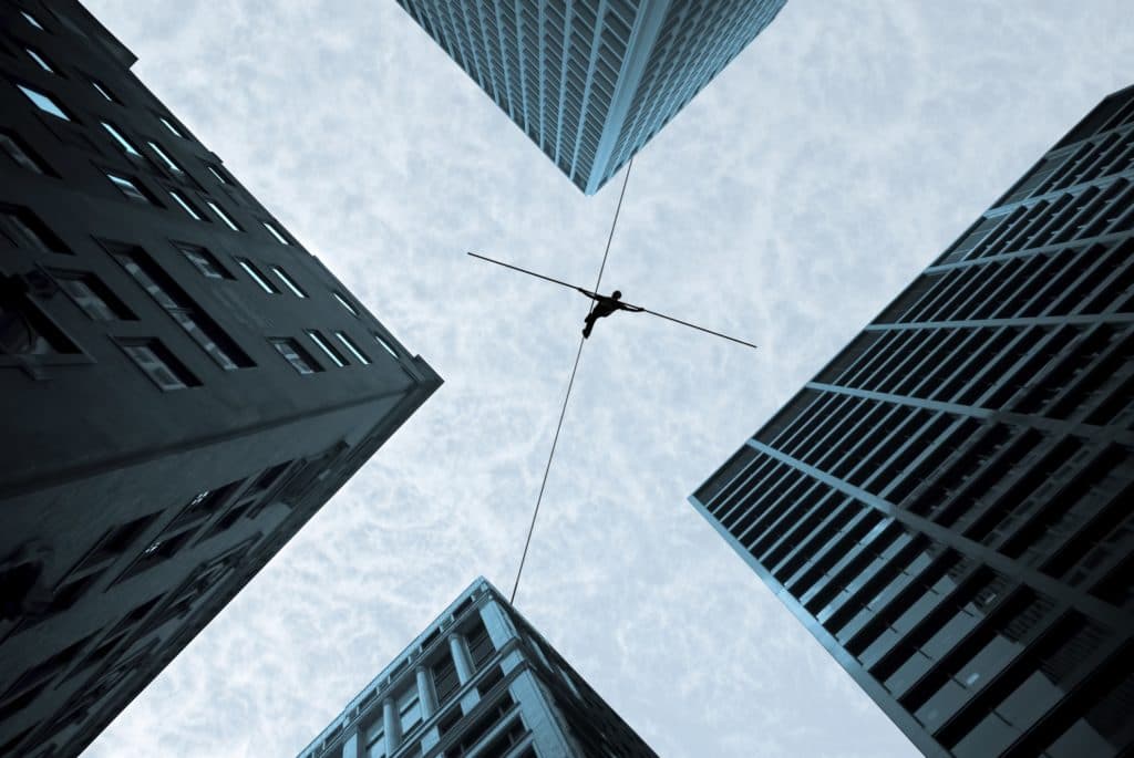 Silhouette of a tightrope walker balancing on a wire stretched between skyscrapers, symbolizing risk-taking, precision, and overcoming challenges in high-stakes environments.