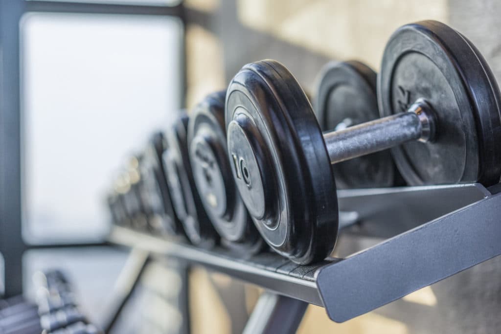 Close-up view of a rack of black dumbbells in a gym, symbolizing fitness, strength training, and exercise equipment.
